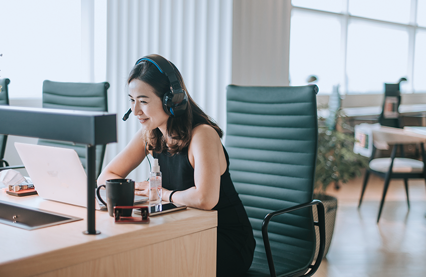 A person working on their laptop computer and talking on their phone