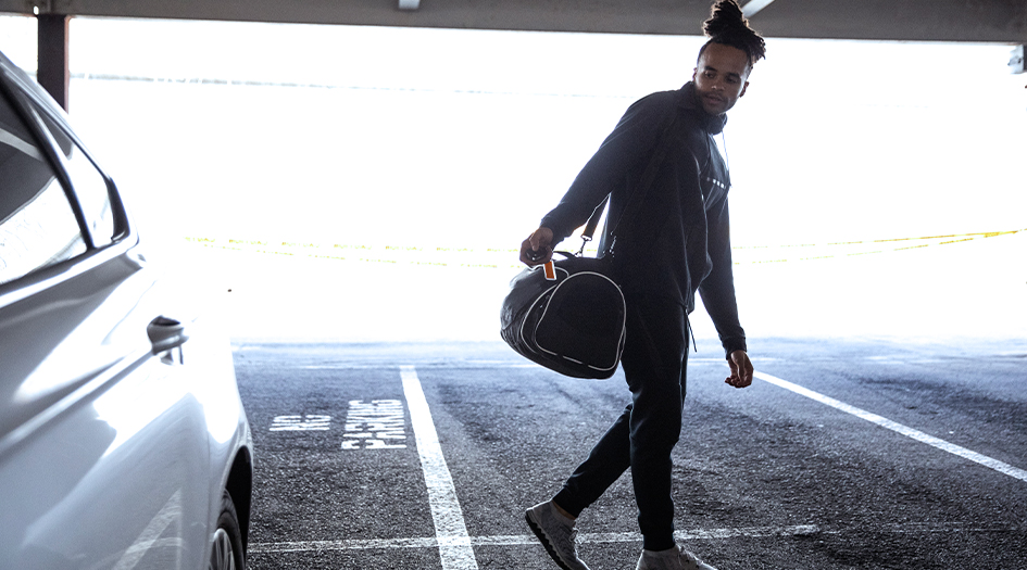 A man locks his car with a gym bag on his shoulder, showing how you can protect your vehicle from electronic car theft
