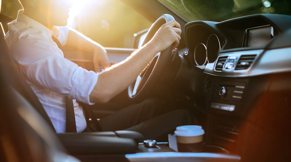 L’assurance auto peut varier si une voiture est louée ou financée, comme en témoigne un homme avec une main sur le volant.