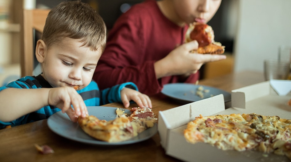 Deux garçons mangent de la pizza, illustrant un des éléments que la formule étendue ou la formule Tous risques peut couvrir.