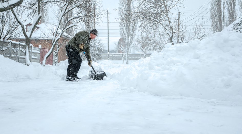 Suivez ces conseils lorsque vous déblayez la neige, comme le démontre cet homme qui déneige son trottoir.